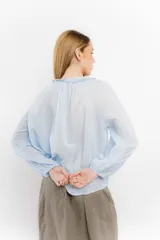 Blusa rosa de algodón con escote en V con cordones y detalle de volados.