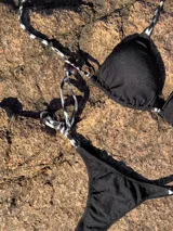 Conjunto de bikini con estampado animal print blanco y negro. El corpiño es de triángulos movibles con tiras finas para atar al cuello y a la espalda, con almohadillas desmontables. La bombacha es colaless con tiras finas para atar a los costados.