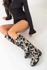 Botas de cuero con estampado animal print de vaca en blanco y negro, con taco de 4cm y caña alta de 37cm.