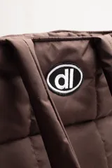 Bolso negro tipo tote bag, acolchado con diseño de cuadrados. Tiene doble asa de hombro y logo estampado en blanco.