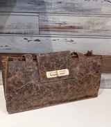 Bolso tote marrón con textura craquelada, cierre con solapa y broche metálico dorado.