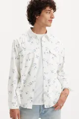 Camisa de hombre de corte relajado, color blanco con estampado floral azul, con cuello clásico, cierre con botones a presión, mangas largas con puños abotonados y dos bolsillos con solapa abotonada en el pecho.