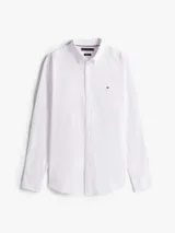 Camisa blanca de corte slim, confeccionada en tejido dobby de algodón elástico con textura sutil. Presenta cuello con botones, puños redondeados con botón y el logo de Tommy Hilfiger bordado en el pecho.