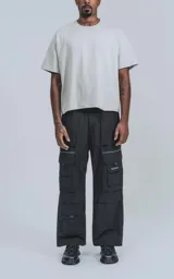 Pantalón técnico negro multipocket con cintura elástica, detalles reflectivos y silueta oversize.
