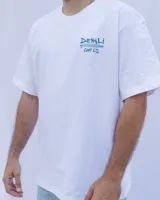 Remera blanca de algodón con cuello redondo y estampado en el pecho con el texto "Denali Surf Co." y una tabla de surf.