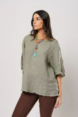 Blusa verde oliva de lino con cuello redondo, mangas cortas amplias con flecos, cierre lateral con botones y ruedo con flecos.