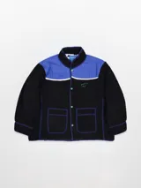 Campera fleece combinada en negro y azul, con cuello alto, cierre de botones a presión y dos bolsillos delanteros.