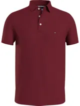 Chomba Tommy Hilfiger de la colección 1985, color borgoña, de corte slim, confeccionada en piqué de algodón elástico. Cuenta con cuello clásico, cartera de tres botones y logo bordado en el pecho.