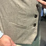 Chaleco azul marino de lana con cuello en V, cierre frontal con botones y bolsillos ribeteados.