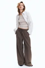 Pantalón marrón de lino, corte holgado, tiro alto, cintura elastizada con cordón ajustable, bolsillos laterales y pierna ancha.