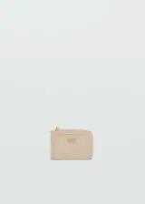Monedero pequeño color beige con cierre de cremallera y logo metálico.