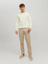 Sweater de punto color crudo, de manga larga y cuello redondo.