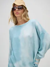 Buzo de algodón con efecto tie-dye en tonos celeste y blanco, de corte holgado y largo por debajo de la cintura, con puños acanalados.