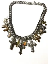 Collar de cadena gruesa plateada con dijes colgantes de cruces y medallones religiosos en tonos plateados y dorados.
