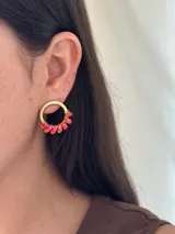 Aros tipo argolla plateados con cuentas de vidrio facetadas en tonos rosa y bordó.