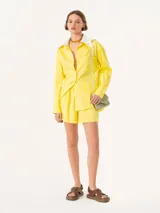 Short amarillo de tiro alto con pinzas delanteras y bolsillos laterales.