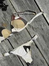 Conjunto de bikini turquesa con corpiño triangular de corte fijo, breteles regulables y almohadillas desmontables, y bombacha vedetina con frunce elástico en los costados.