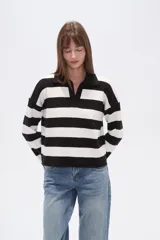 Sweater de tejido de punto, holgado, con rayas horizontales anchas en blanco y negro. Presenta cuello polo con escote en V y mangas largas.