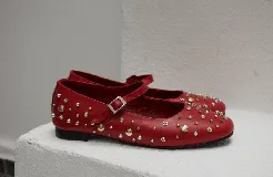 Chatas negras de cuero con correa sobre el empeine y hebilla plateada. Decoradas con tachas plateadas y doradas de diferentes tamaños.