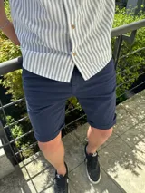 Bermuda de gabardina azul marino con ruedo doblado.