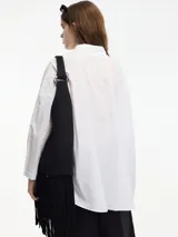 Camisa blanca de algodón con cuello camisero y botones frontales.