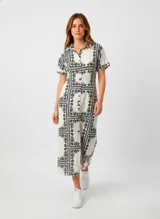 Vestido largo de algodón, manga corta, con cuello camisa y lazo ajustable en la cintura. Presenta un estampado de pañuelo en blanco y negro dispuesto en bloques cuadrados.