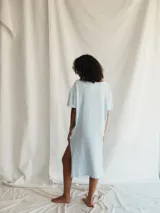 Vestido camisero celeste de algodón reciclado, corte recto, largo midi con tajo lateral y mangas cortas.