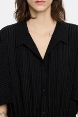 Mono largo negro de viscosa con textura, corte ajustado en la cintura, cuello camisero con solapa, manga corta recta descosida por el bajo y cierre frontal con botonadura. Cintura ajustable con cordones de tejido.