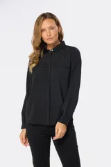 Blusa tipo camisa blanca con estampado de pequeñas flores negras, manga larga, botones nacarados ocultos con cartera y doble capa en el frente para evitar transparencias.