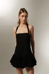 Vestido mini negro sin mangas de algodón, con cuello recto, corte ajustado y falda con volados.