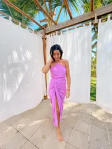 Vestido largo lila con escote halter cruzado en la espalda y falda tipo pareo con abertura lateral y nudo decorativo.