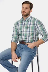 Pantalón de jean azul oscuro de corte recto y tiro medio. Incluye cinturón de cuero marrón y botas de gamuza marrón.