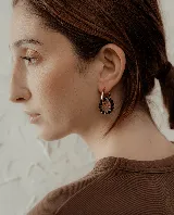 Par de aros colgantes con argolla dorada y dije circular con cuentas de cristal rojas y violetas.