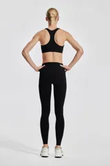 Calzas deportivas negras de tiro alto con bolsillos laterales, confeccionadas en tejido funcional DryMove™ que absorbe la humedad.