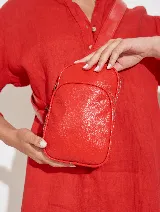 Bandolera roja de cuero sintético, con correa ajustable y cierre superior.