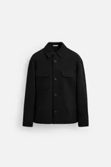 Sobrecamisa negra de corte relaxed fit, con cuello solapa, manga larga con puños abotonados, bolsillos de plastrón con solapa en el pecho y bolsillos de vivo en la cadera. Cierre frontal con botones.