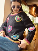 Sweater artesanal tejido en lana, con corazones de crochet en colores vibrantes.
