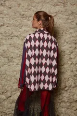 Camisa holgada con estampado de rombos en tonos rosa y marrón, con cuello solapa y abotonada. Tiene mangas largas con rayas verticales en tonos borgoña y violeta.