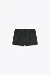 Shorts de tiro alto color negro con textura de gamuza, bolsillos delanteros y cierre frontal con cremallera y ganchos metálicos.