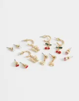 Set de seis pares de aros dorados con diferentes diseños: aros tipo botón con forma de manzana roja, perla, strass rosa; y aros colgantes con forma de corazón, mariposa y cereza.