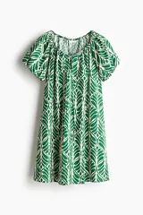 Vestido corto evasé de algodón con estampado de hojas verdes. Tiene mangas globo cortas de diseño raglán, escote redondo con cordón para ajustar y corte holgado.