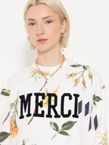 Buzo blanco estampado con flores y la palabra "MERCI" en el frente.
