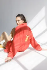 Campera bomber color coral confeccionada en mezcla de algodón y lino, con cierre frontal y bordado grande en la espalda inspirado en la colección La Verdulería.