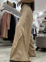 Pantalón palazzo color beige con textura arrugada y aberturas triangulares en el frente de cada pierna.