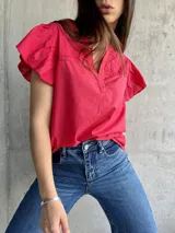 Blusa roja de manga corta con volantes y detalles bordados en el pecho.