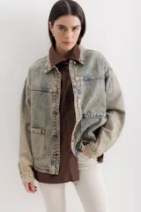 Campera de jean celeste con efecto lavado, corte recto, cuello clásico, cierre frontal con botones metálicos, bolsillos de parche en el pecho y mangas largas con puños abotonados.