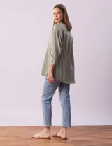 Blusa verde con rayas verticales blancas, cuello a la base y escote en V con aplique de botones. Manga ¾ con puño y botón. Tajo en costuras laterales.