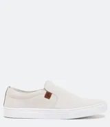 Championes slip on color crudo, con elásticos laterales y detalle de etiqueta marrón con logo en el lateral.