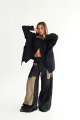 Pantalón de jean negro de corte acampanado, con parches de pana color visón y cordones en la cintura.