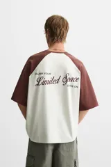 Camiseta blanca con mangas cortas marrones tipo ranglán, cuello redondo y estampado con la frase "Inner Peace" en marrón.